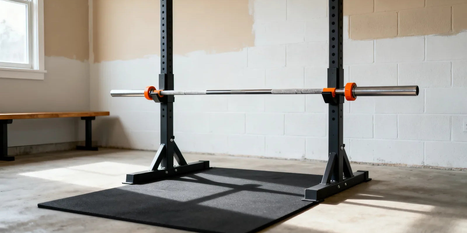 A plain barbell set at hip height in a squat rack above an empty rubber mat in a home garage gym, the starting setup for an inverted row